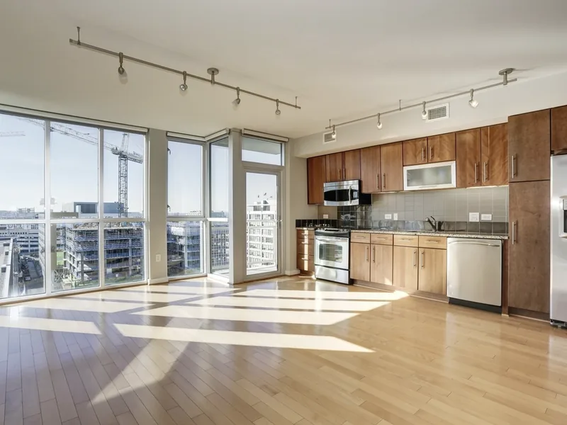 An empty, sunlit apartment with a kitchen