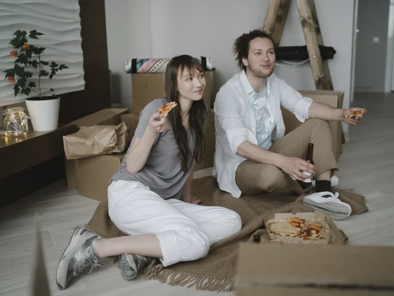 A couple sharing pizza on the floor of their new home