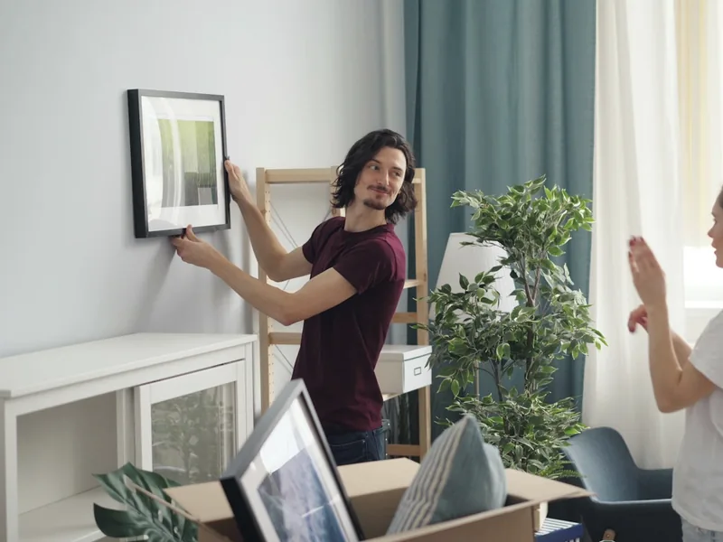 A man taking down a framed picture while packing