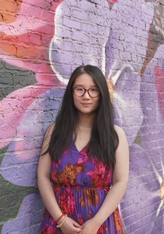 Greenie Gai in front of a flower mural
